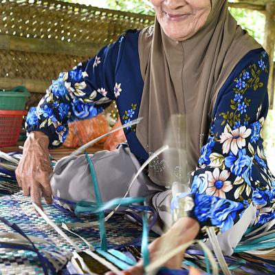 Mak Lang demonstrates how to weave a mat.